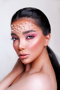Striking portrait of a woman with pearl-studded creative makeup highlighting elegance and beauty.
