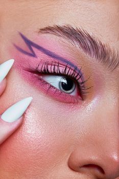 Vibrant close-up of eye makeup with creative eyeliner in a studio setting.