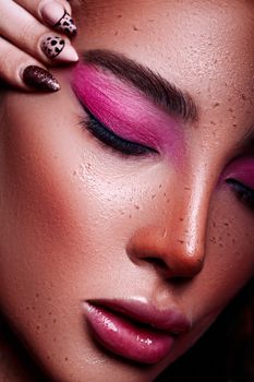Stunning close-up shot of a woman with bold makeup and freckles in a studio setting.