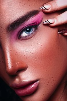 A striking close-up shot showcasing bold makeup and natural freckles in a studio setting.