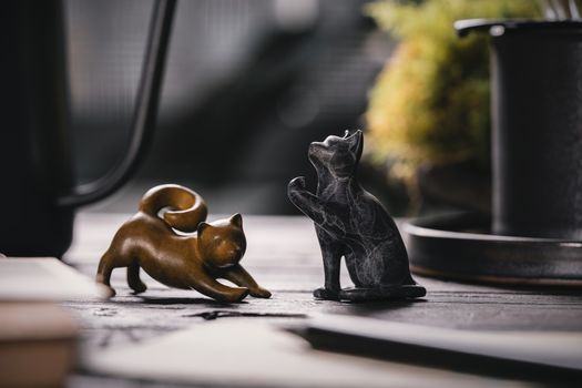 Artistic close-up of golden and black cat figurines creating a charming tabletop scene.