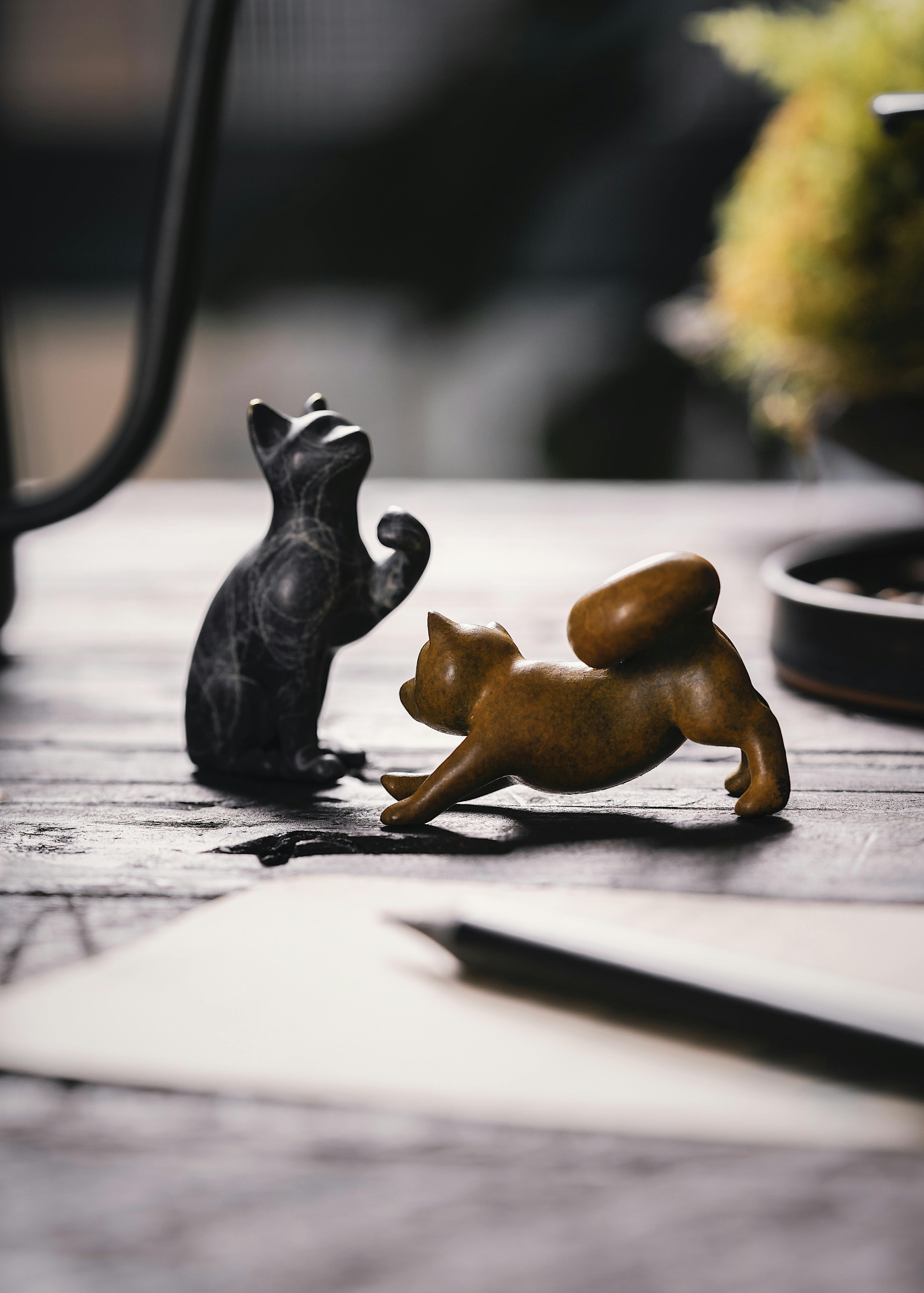 Close-up of black and golden cat figurines on a wooden table, artistic decor.