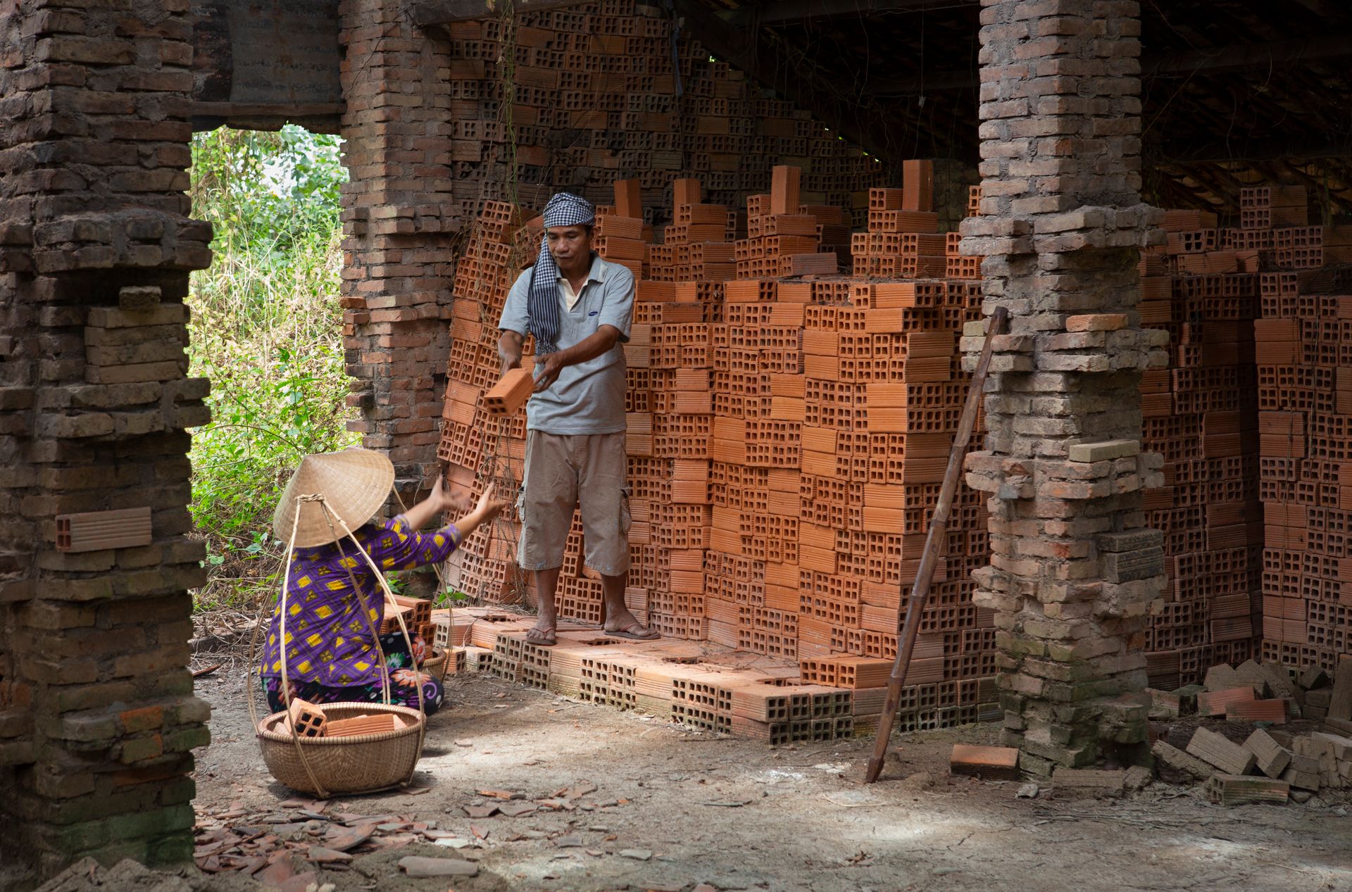 A man and woman working together in a rural brick factory setting.