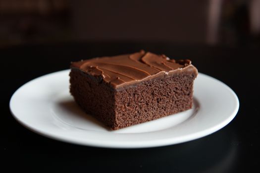 Close-up of a chocolate brownie slice on a white plate, perfect for dessert lovers.