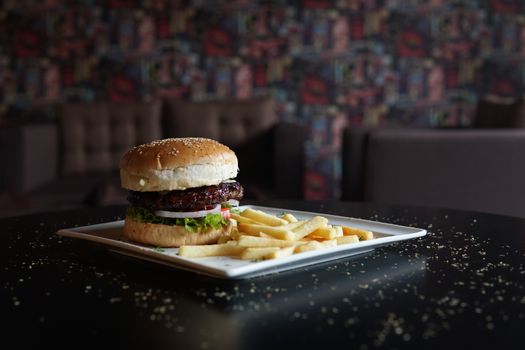 Close-up of a gourmet burger with fries served on a tray in a cozy restaurant setting.