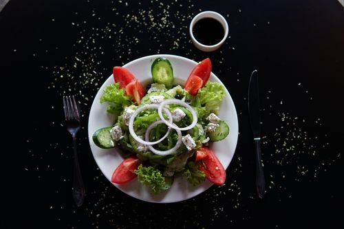 Free Top view of a vibrant Greek salad with feta, lettuce, and tomato slices on a dark table. Stock Photo