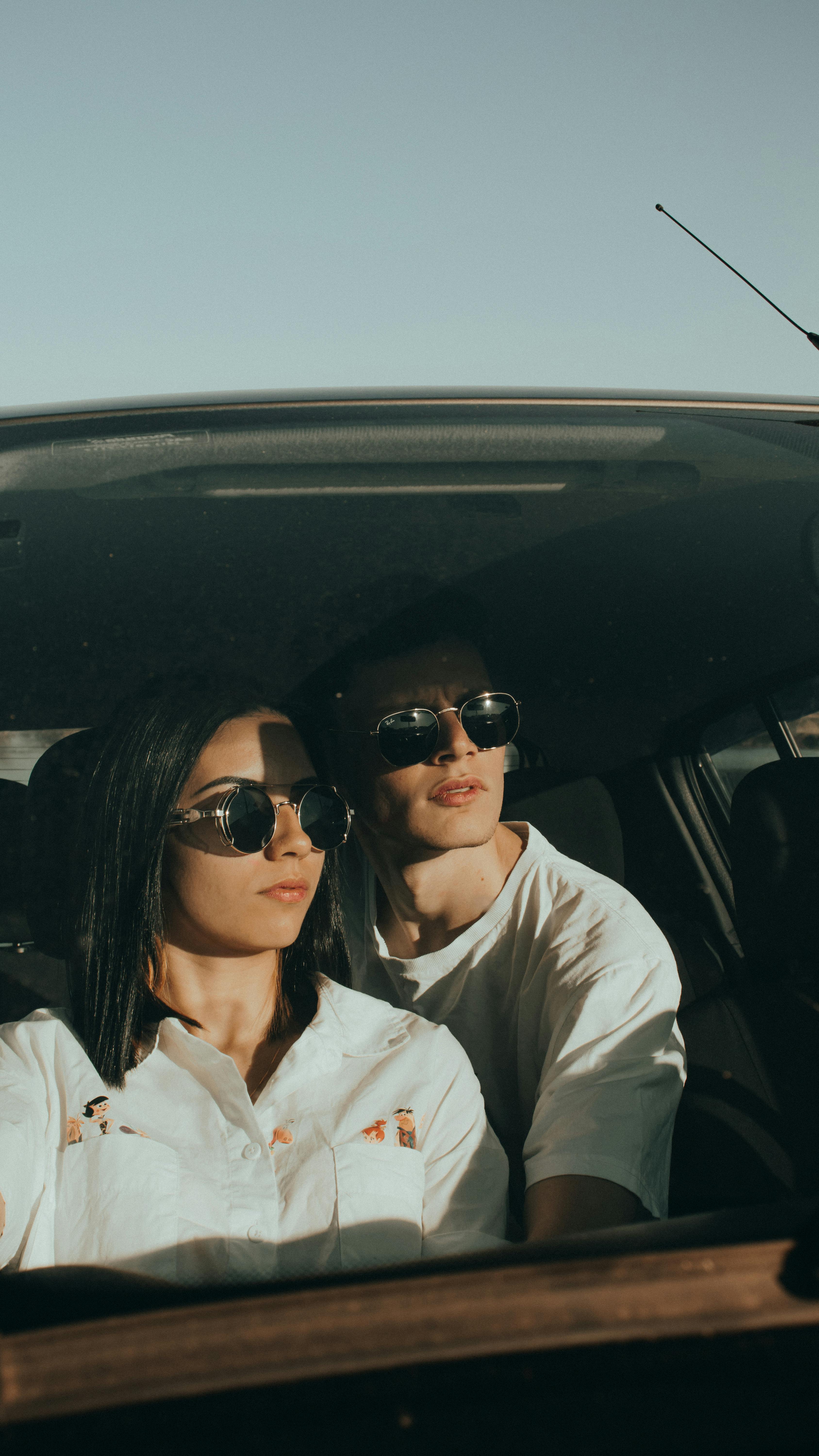 A young couple wearing sunglasses enjoying a drive on a sunny day.