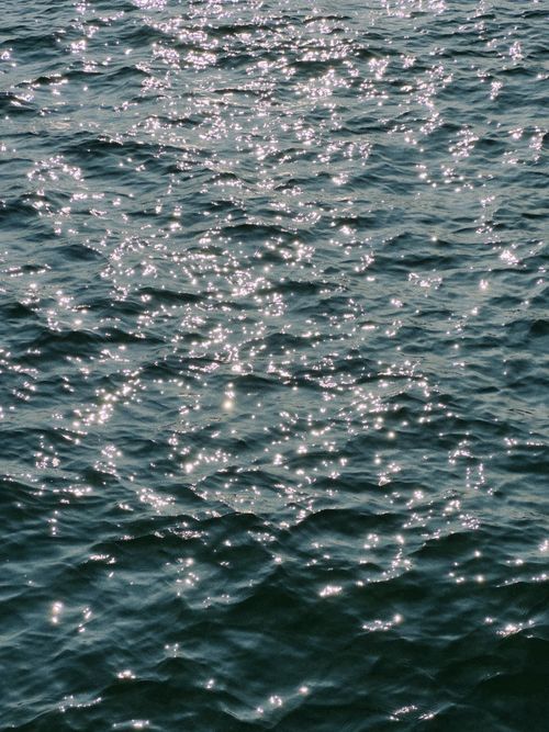 Free Sparkling sunlight reflecting on the deep blue ocean waves, creating a natural pattern of shimmering light. Stock Photo