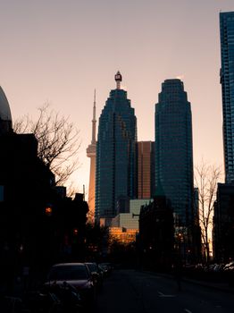 Dramatic view of Toronto's skyline at sunset with the CN Tower and skyscrapers, showcasing urban architecture.