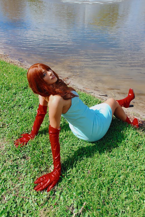Woman in Red Gloves and Boots Sitting on Grass at the River
