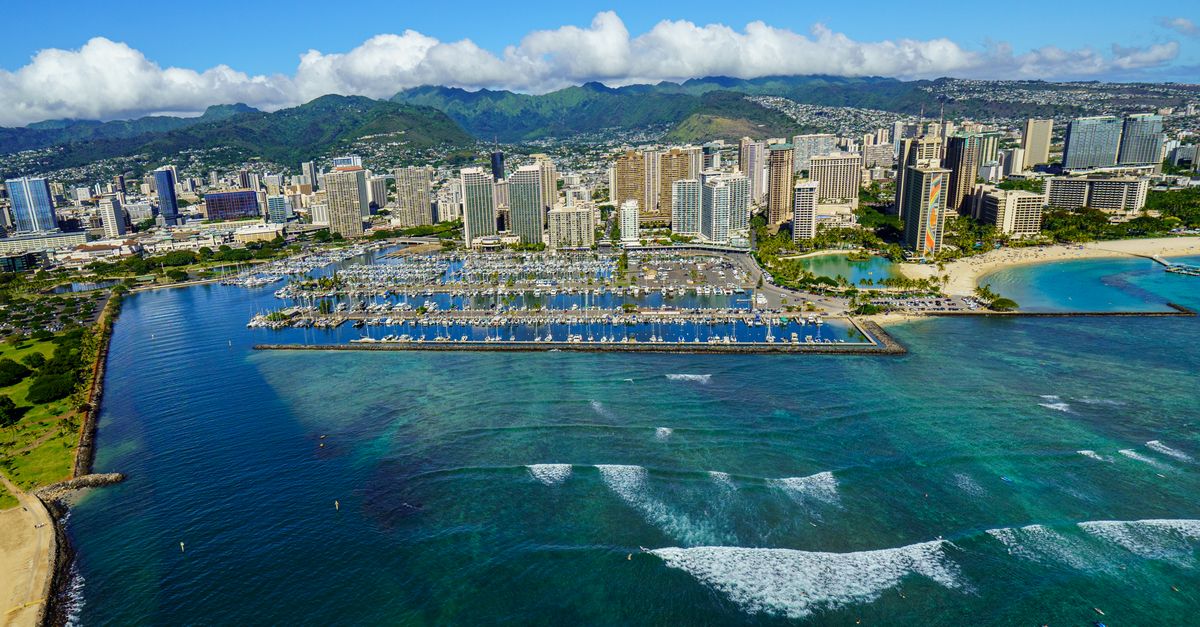 Stunning aerial shot of Honolulu's skyline with the iconic Waikiki Beach and harbor in vibrant daylight.