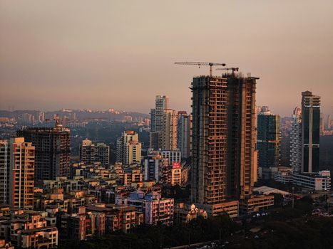 Photo by Ratnesh Tiwari A vibrant cityscape with high-rise buildings and active construction at dusk.
