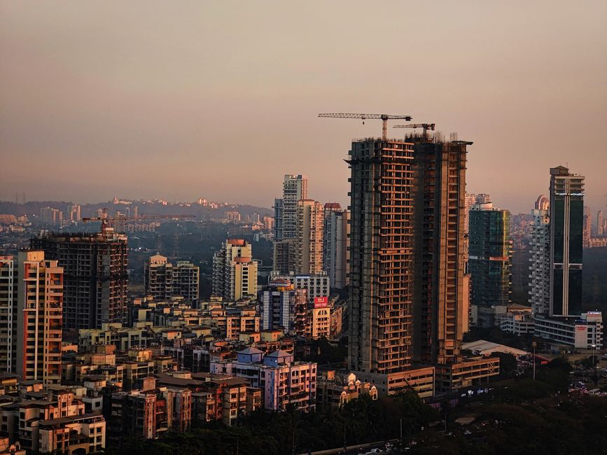 Photo by Ratnesh Tiwari A vibrant cityscape with high-rise buildings and active construction at dusk.