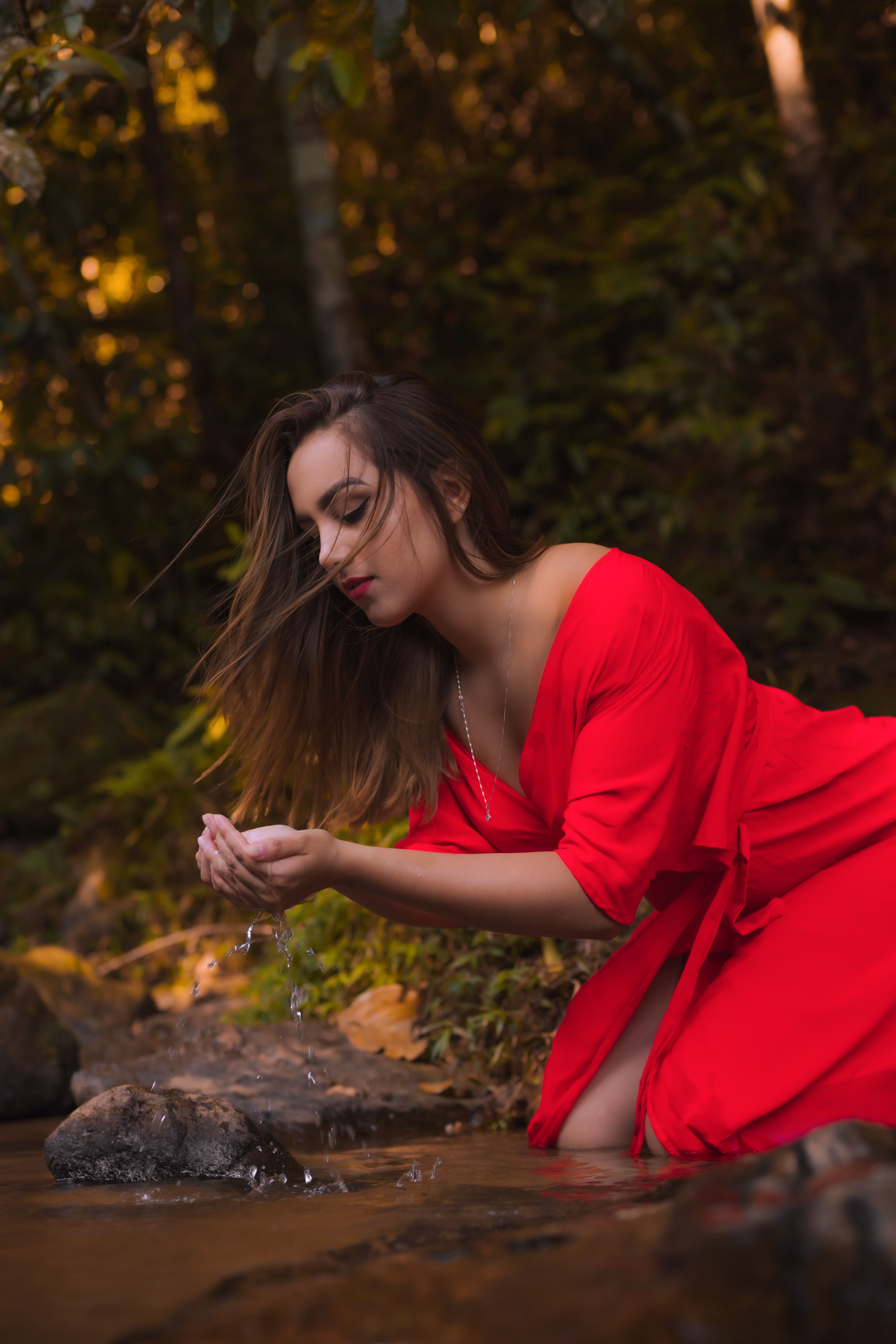 Woman in Red Dress Kneeling by River · Free Stock Photo