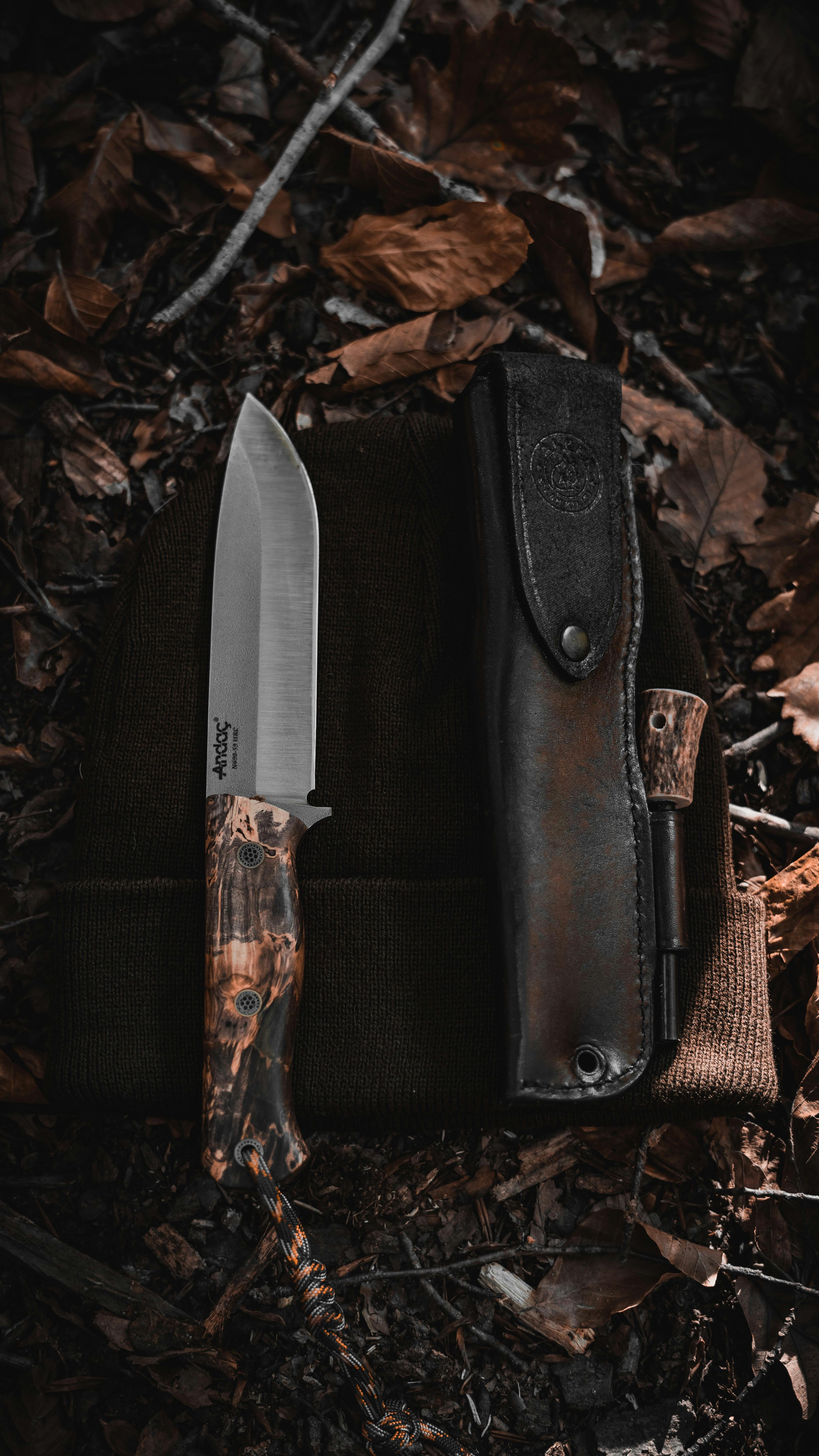 Close-up of a survival knife with sheath on a forest floor in Bolu, Türkiye.