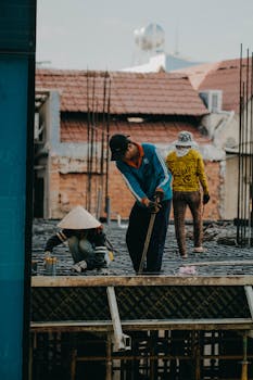 A team of construction workers engaged in building a structure in an urban area, showcasing teamwork and industry.