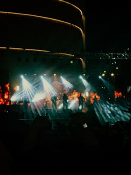 Silhouetted band performing at night with dramatic stage lighting and effects.