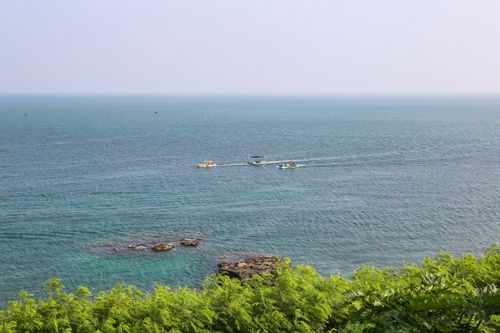 Free Peaceful ocean view with boats and lush green coastline under a clear sky. Stock Photo