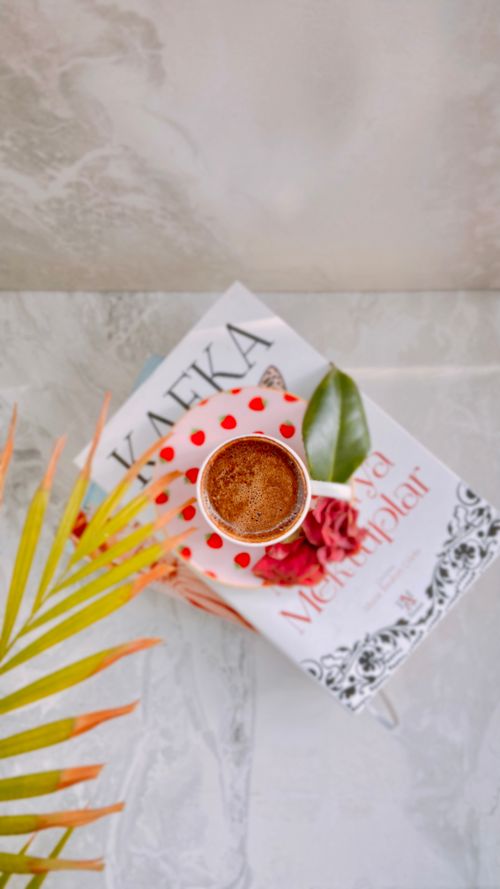 Free A cup of coffee on a book surrounded by a leaf, providing a cozy reading vibe. Stock Photo