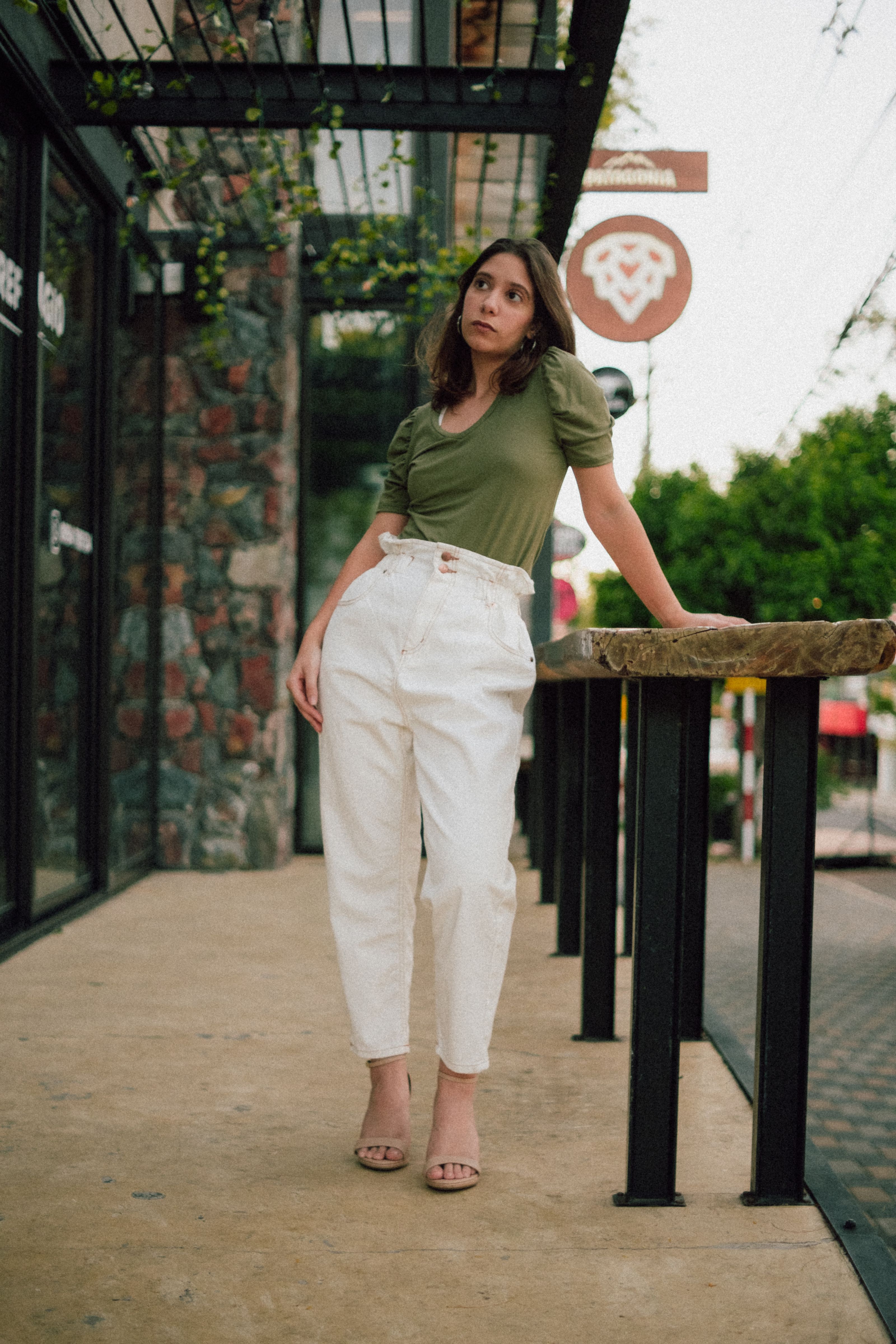 Uma jovem fashionista posa com confiança em um look casual e chique em uma calçada urbana.