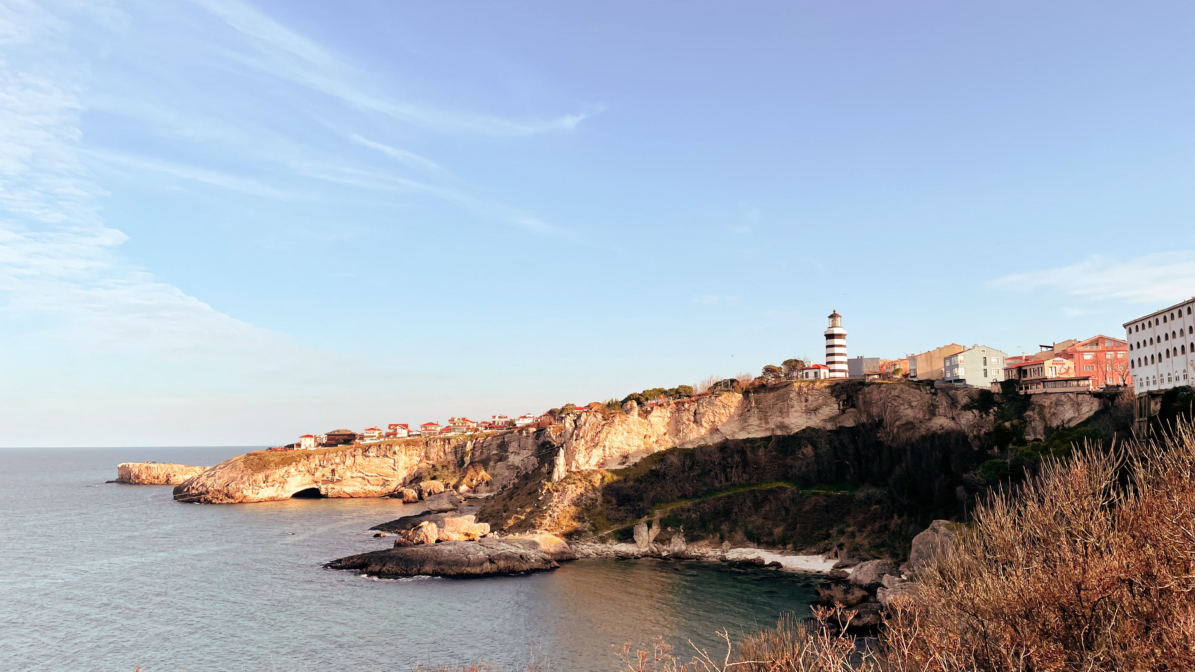 Beautiful view of the Şile lighthouse on the rocky Turkish coastline under a clear blue sky.