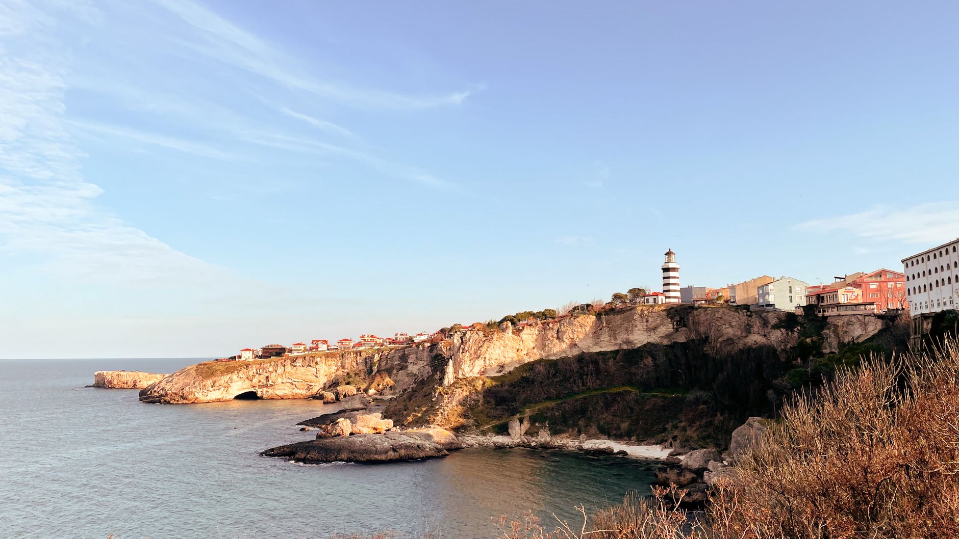Beautiful view of the Şile lighthouse on the rocky Turkish coastline under a clear blue sky.