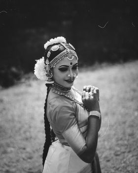 A stunning black and white portrait of a traditional Indian dancer showcasing intricate makeup and jewelry.
