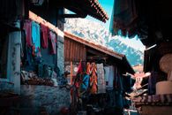 Explore vibrant textiles and crafts in the market of Krujë with a stunning mountain backdrop.