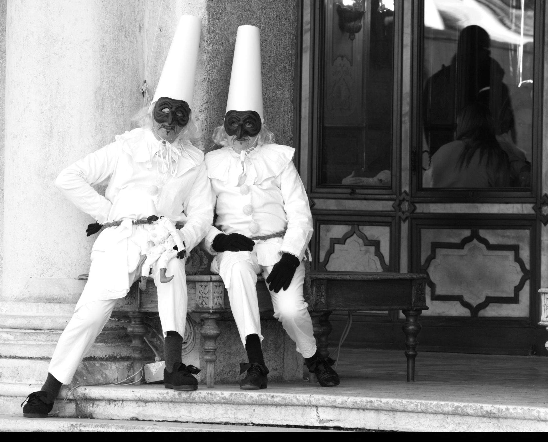 Black and white photo of masked performers in Venice displaying traditional costumes.