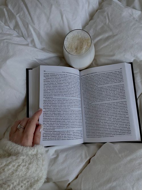 Free A person enjoying a book and coffee in the comfort of a cozy bed. Stock Photo