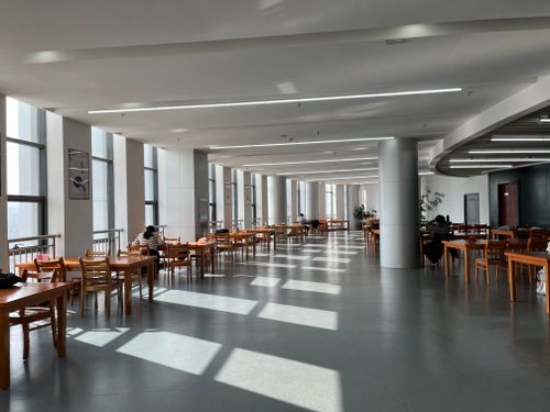 Free A modern university canteen in China with wooden tables and natural daylight streaming in. Stock Photo