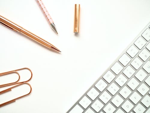 Free Pens Near Keyboard and Paper Clips Stock Photo