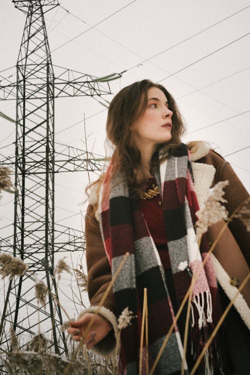 Young Woman on a Field in Winter Wearing a Jacket and a Checkered Scarf 