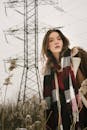 穿着保暖衣服的年轻女子在冬日田野里举着电线杆摆姿势