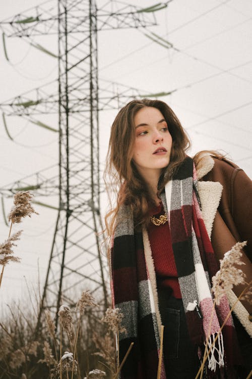 Young Woman on a Field in Winter Wearing a Jacket and a Checkered Scarf 