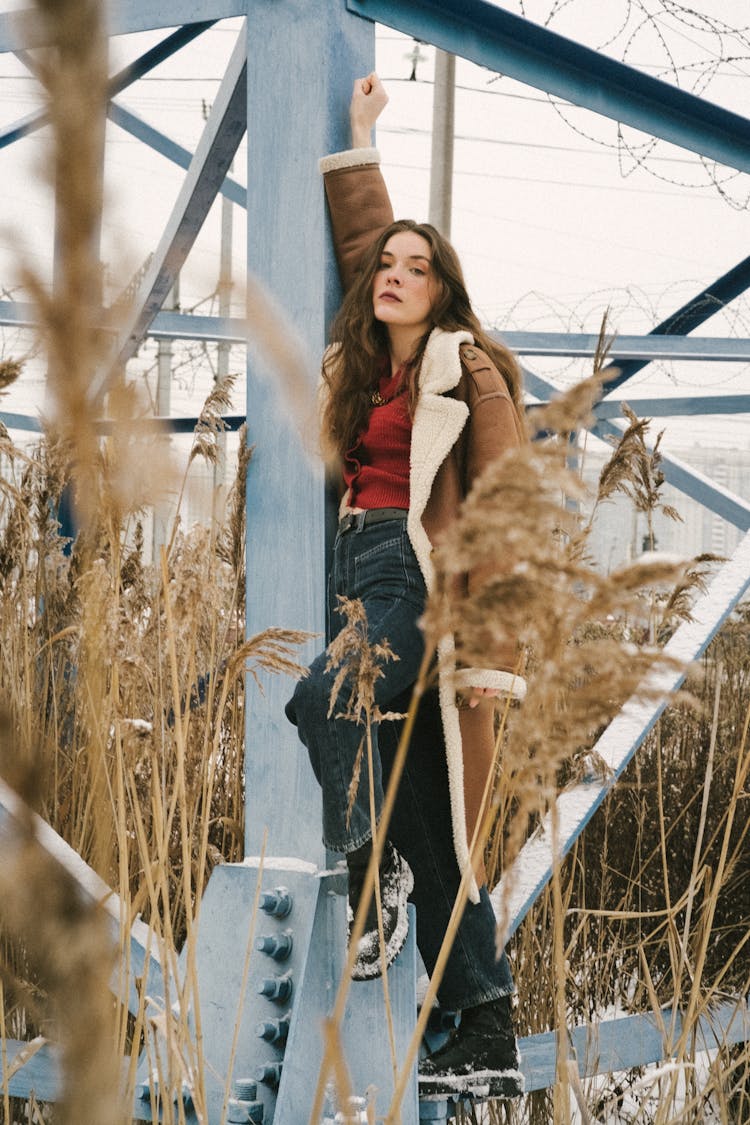 Young Woman Leaning Against A Utility Pole On A Field In Winter 