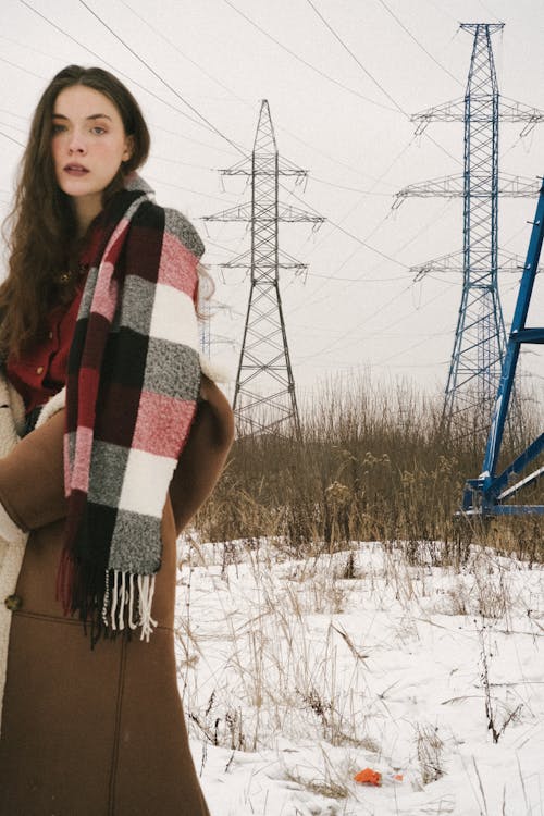 Young Woman on a Field in Winter Wearing a Jacket and a Checkered Scarf 