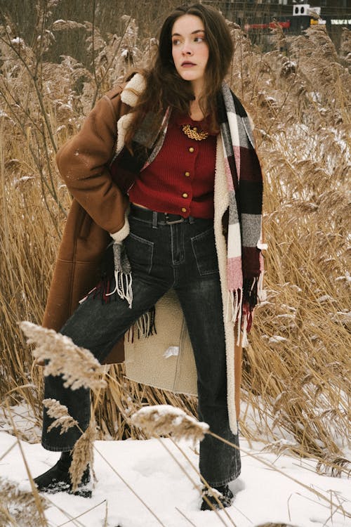 Young Woman on a Field in Winter Wearing a Jacket and a Checkered Scarf 