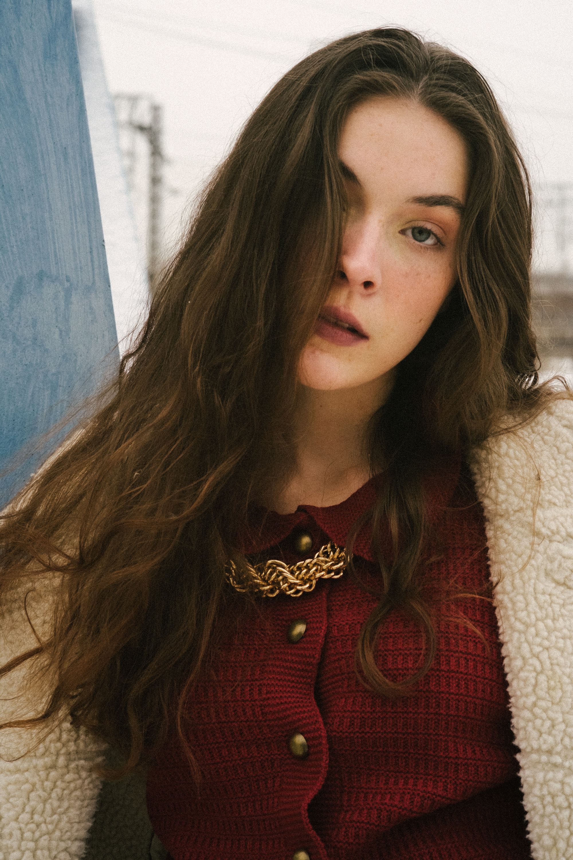 Elegant portrait of a woman with long brunette hair in a cozy sheepskin coat on a winter day.