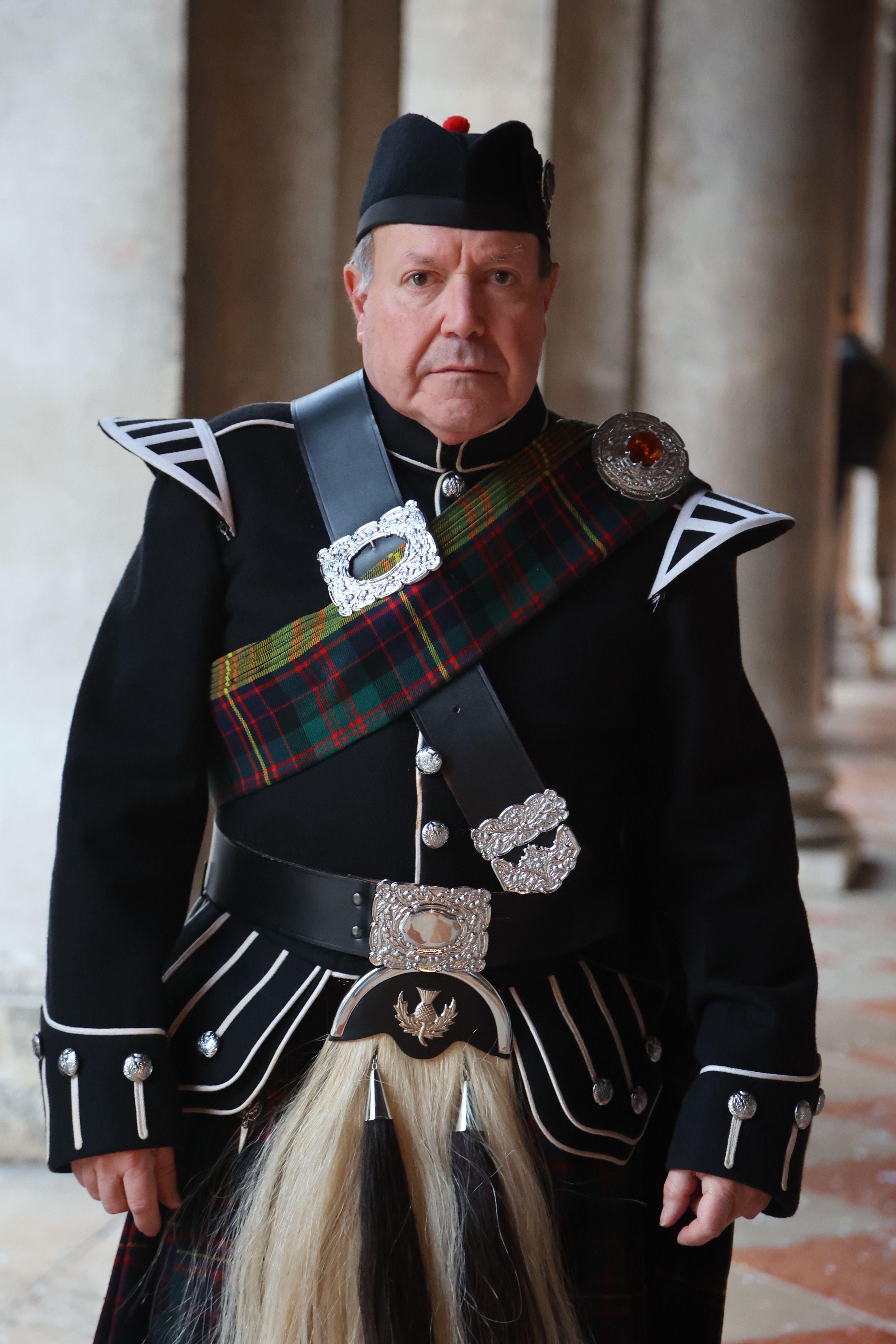Man in traditional Scottish attire at the Venice Carnival, indoors.