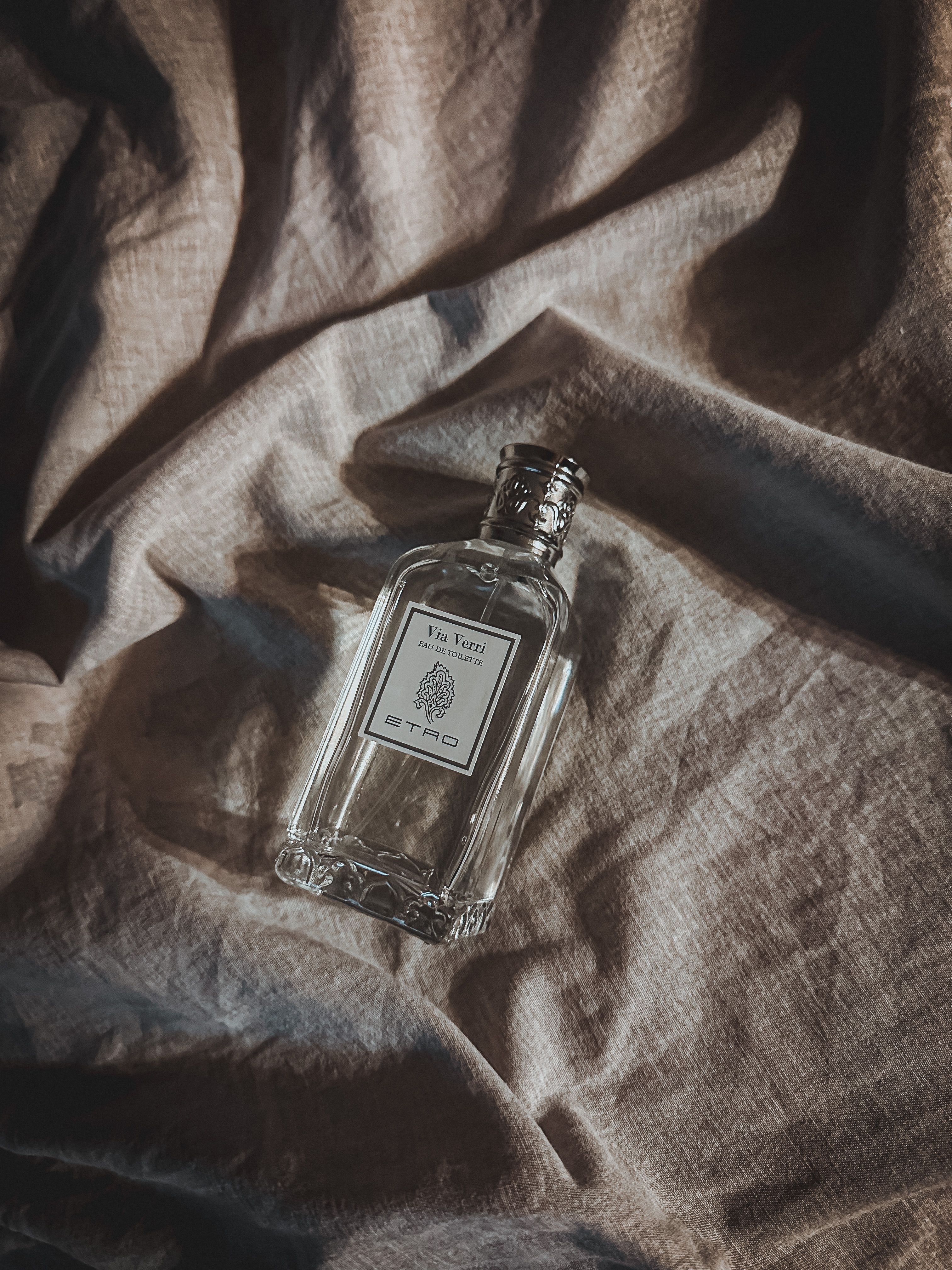 Sophisticated perfume bottle resting on luxurious textured fabric, casting gentle shadows.