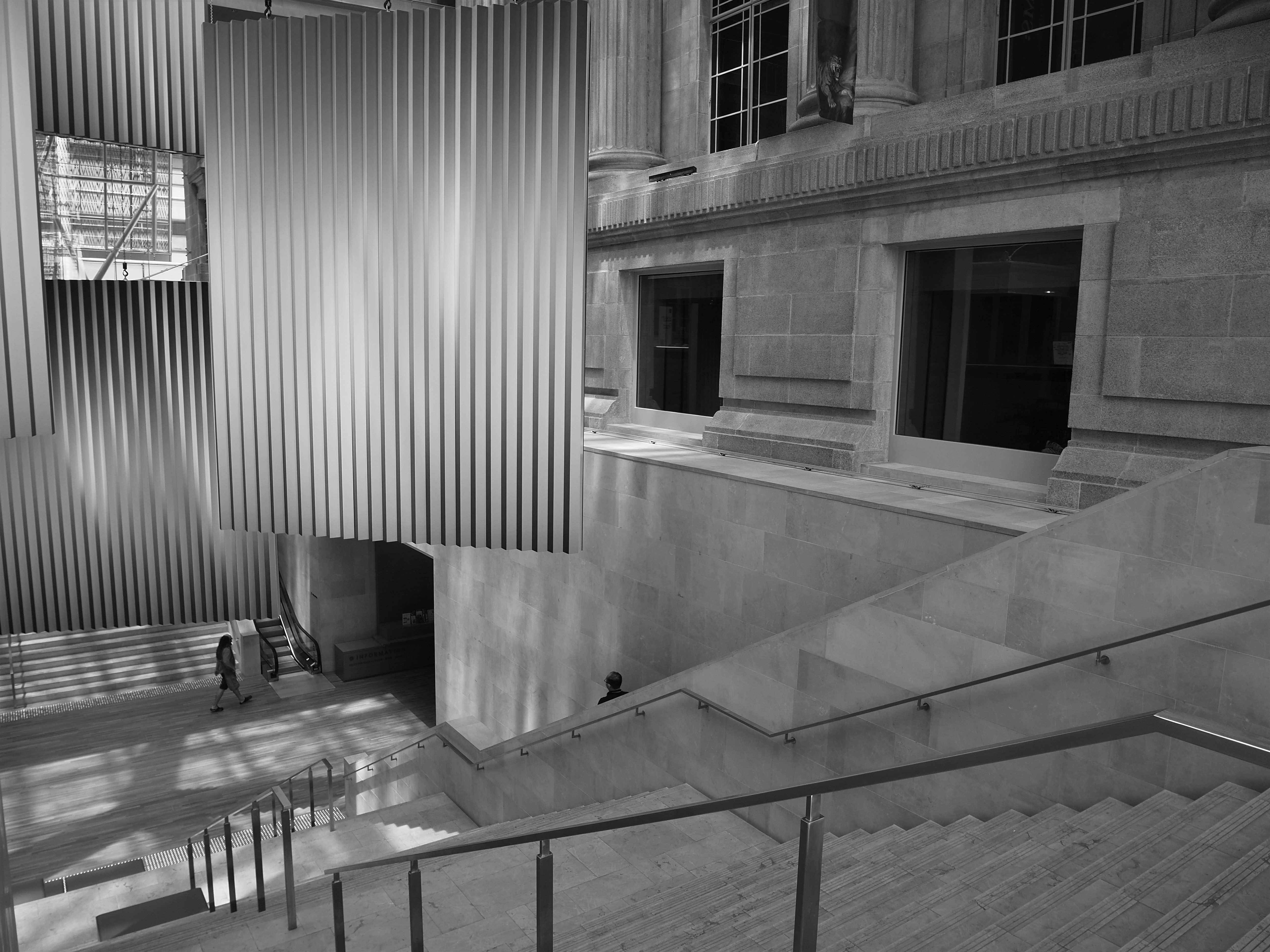 Stunning black and white image of a modern museum interior with stairs and large windows.