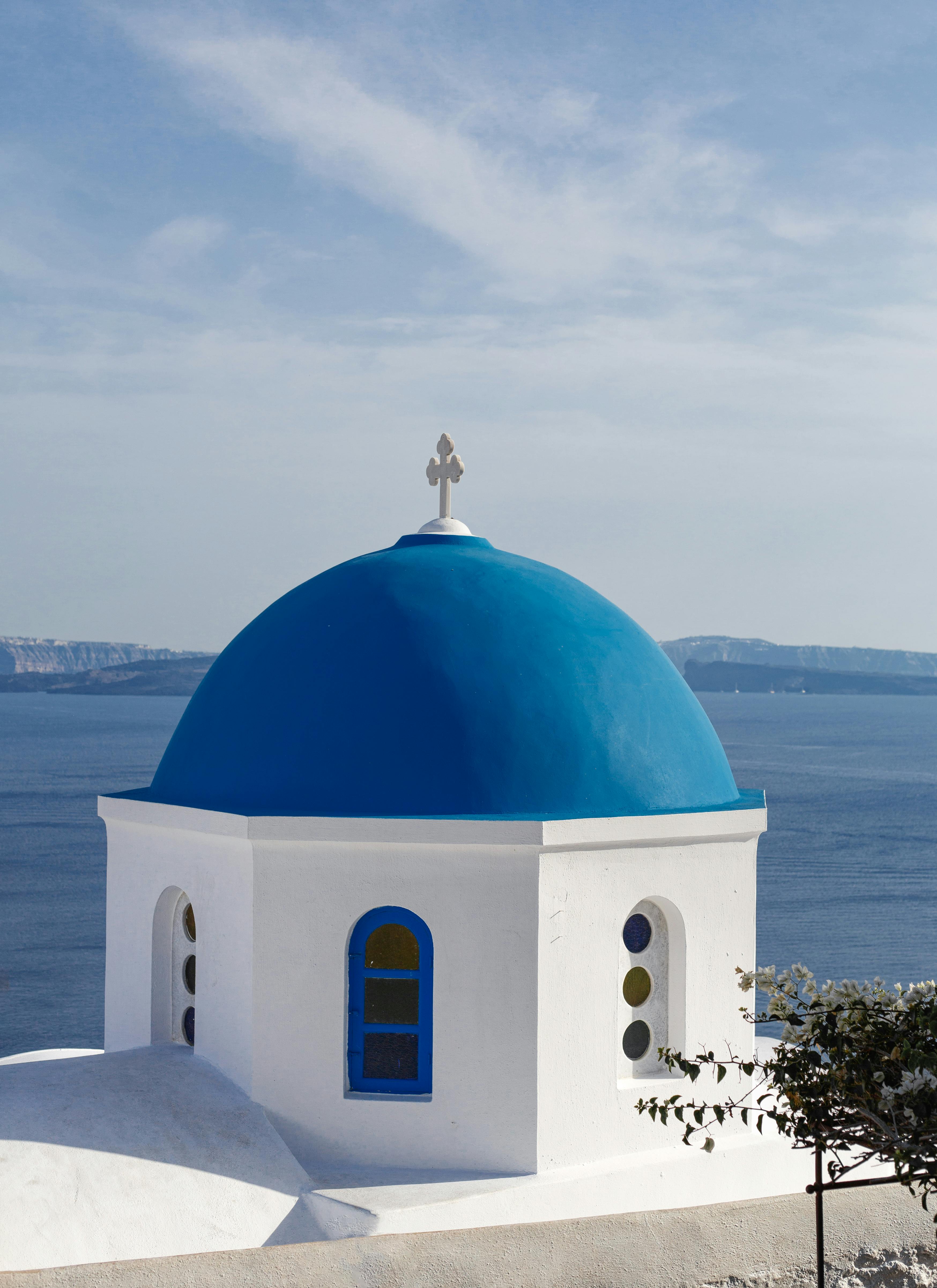 Breathtaking view of a blue-domed church in Santorini, Greece with the Aegean Sea in the background.