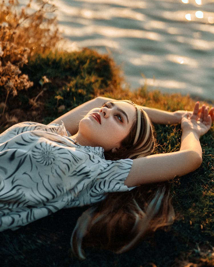 Woman Lying On Grass By Sea