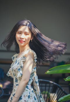 一位穿着花卉连衣裙的年轻女子，在阳光下享受着微风，头发随风优雅地飘逸