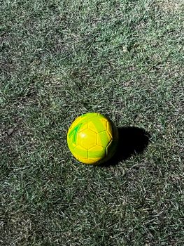 Bright yellow soccer ball lying on green grass during daytime in Birmingham, capturing the essence of outdoor sports.