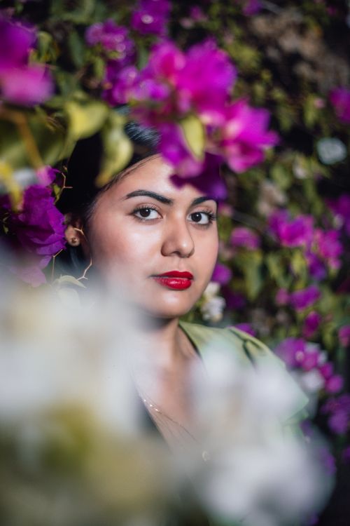 Free A woman with red lipstick surrounded by vivid bougainvillea flowers, creating an artistic and colorful portrait. Stock Photo
