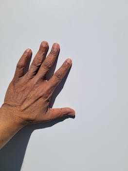A close-up of an adult's hand against a white background, showing details and texture.