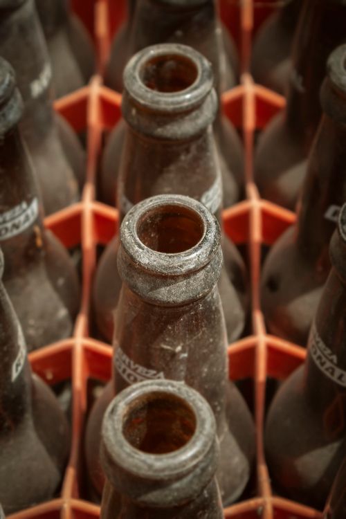 Free A detailed high angle shot of empty beer bottles arranged neatly in an orange crate. Stock Photo