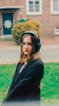 Brunette young woman with headphones enjoying music outdoors in a park.